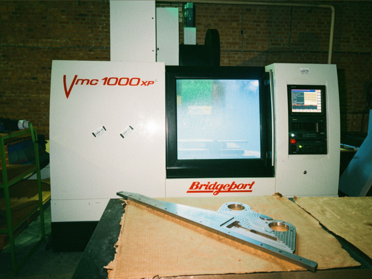 De Bridgeport VMC 1000 XP met gefreesde onderdelen op de werkbank ervoor.